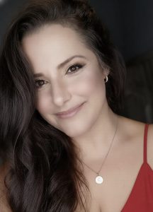 אסנת הראל המנחה בחולצה אדומה 